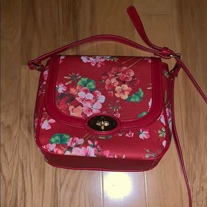 A red purse with pink and peach colored flowers